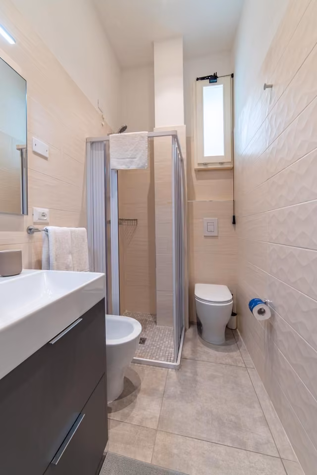 Bagno con doccia e rivestimenti chiari